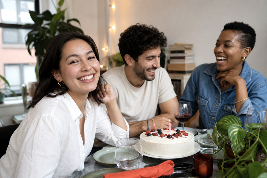 Friends laughing around a birthday cake